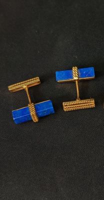 trois paires de boutons de manchette dorés et bleus sur fond noir