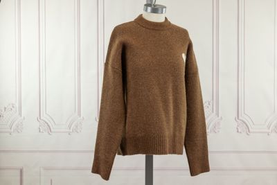 brown sweater on a mannequin stand in front of a white wall