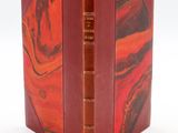 an old book with a red cover and a brown cover