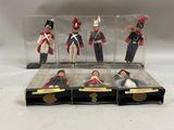 quatre petits soldats en plastique sont exposés dans une vitrine posée sur une surface blanche