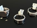 three silver rings with tags on them sitting on a black surface