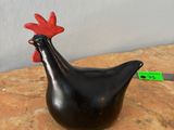 un poulet noir posé sur une table, à côté d'un couteau