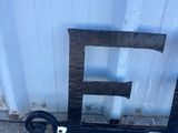 une lettre « e » en bois posée par terre près d'un mur métallique