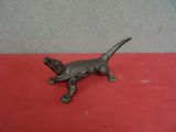 une vieille figurine de lézard en bronze posée sur une surface rouge