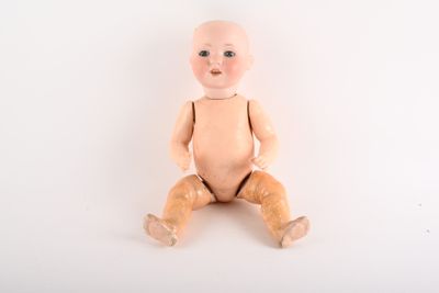 une poupée assise par terre, les jambes croisées