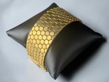 black and gold leather pillow with a gold honeycombe band