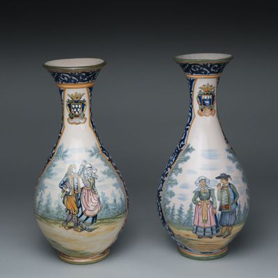 une paire de vases décorés de personnages, posés sur une table