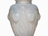 un vase blanc orné d'un visage, posé sur une surface blanche