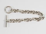 a close up of a silver chain with a key on a white surface