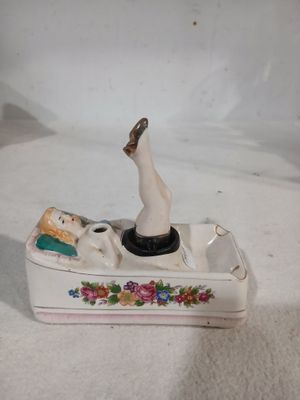 une figurine représentant une femme dans un bateau, posée sur une surface blanche