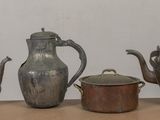 several antique teapots and pots are lined up on a table