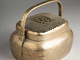 an old brass teapot with a handle on a white surface