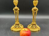 deux bougeoirs dorés posés à côté d'une pomme sur une table