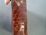 a person holding a brown alligator skin purse in their hand