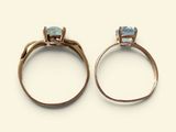 two gold rings with a blue topaz stone on each side