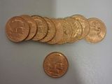 un gros plan sur un tas de pièces d'or à côté d'un penny