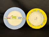 two plates with animals painted on them sitting on a black surface