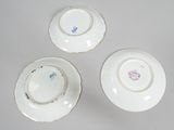 three white plates with blue and pink designs on them on a white surface