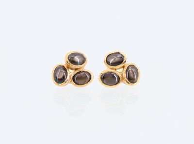 une paire de boucles d'oreilles en or ornées de pierres noires sur fond blanc