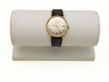 un gros plan d'une montre-bracelet posée sur un présentoir blanc