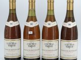 quatre bouteilles de vin sont alignées sur une surface blanche