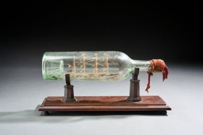 une bouteille en verre contenant un bateau, posée sur un socle en bois
