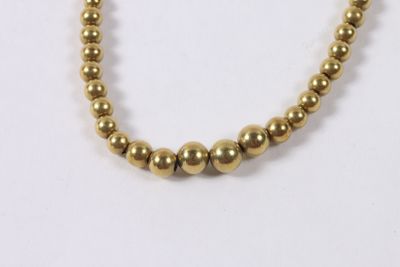 un gros plan d'un collier de perles dorées sur fond blanc