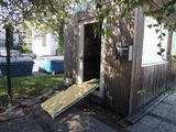 a small wooden outhouse with a ramp in front of it