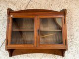 a small wooden cabinet with glass doors on the wall