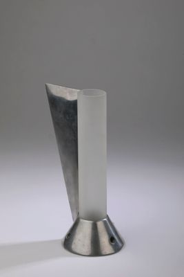 a silver vase sitting on a white surface with a gray background