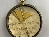 a small gold clock with writing on it on a white surface