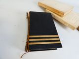 un livre noir orné de bandes dorées, posé à côté d'une boîte remplie de livres