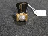a gold ring with a diamond on it on a black surface