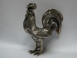 un coq argenté posé sur une surface blanche