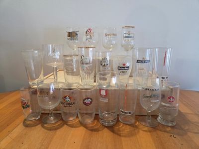 bottles and glasses are lined up on a table in front of a white wall