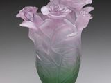 un vase en verre violet et vert contenant des fleurs, posé sur une table