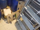 une échelle métallique qui se trouve à côté de quelques fûts bleus