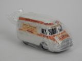 une petite camionnette miniature emballée dans du plastique, posée sur une surface blanche