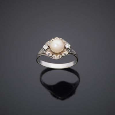 a white pearl and diamond ring on a black surface