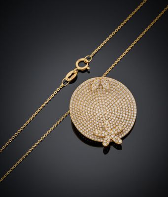 un collier en or avec un pendentif circulaire et une chaîne, sur fond noir