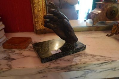 une statue représentant une main tenant un livre posé sur une table en marbre