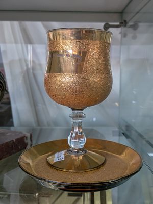 une table en verre sur laquelle se trouvent une assiette dorée et un verre