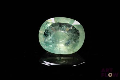 a close up of a green gemstone on a black surface