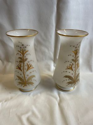 deux vases blancs ornés de motifs dorés, posés sur un tissu blanc