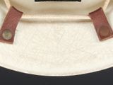 a white plate with a brown leather strap on it