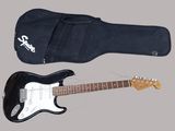 une guitare électrique noire et un étui noir sur fond gris
