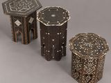trois petites tables en bois ornées de motifs complexes sur fond gris