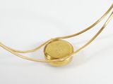 a gold necklace with a coin on it on a white surface