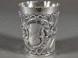a close up of a silver cup on a table with a silver background