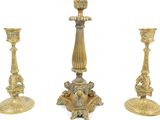 three gold colored candlesticks sitting next to each other on a white surface